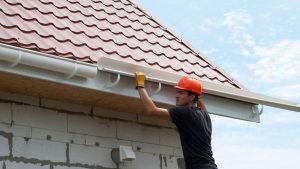 worker installs the gutter system on the roof